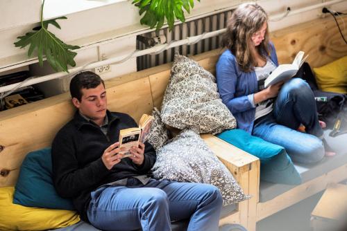a man sitting on a bed with two women reading at Sleep in Heaven in Copenhagen