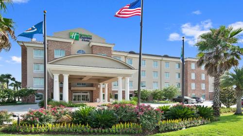 a hotel with two flags in front of a building at Holiday Inn Express & Suites Gonzales by IHG in Gonzales