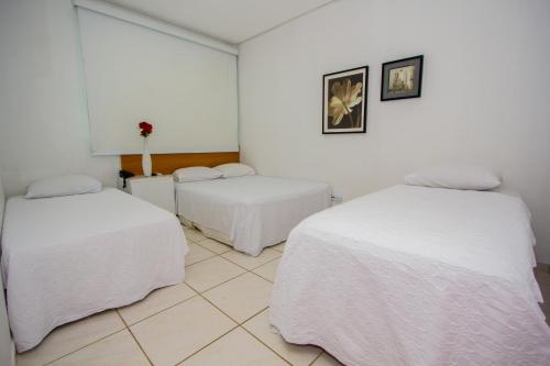 two beds in a room with white sheets at Hotel Talissa 2 in Manaus