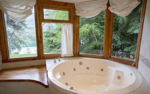 uma grande banheira num quarto com janelas em BOG Le Pommier - Cabañas con vista al lago y piscina climatizada em Villa La Angostura