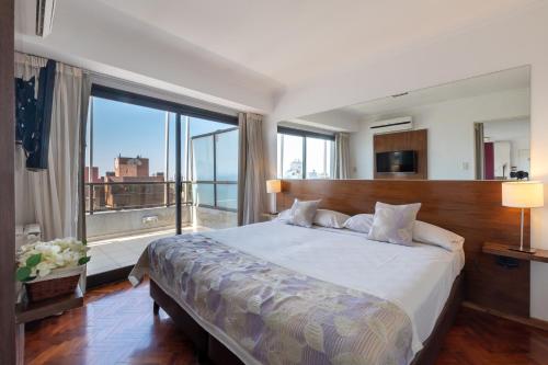 a bedroom with a large bed with a large window at AT Suites in Córdoba