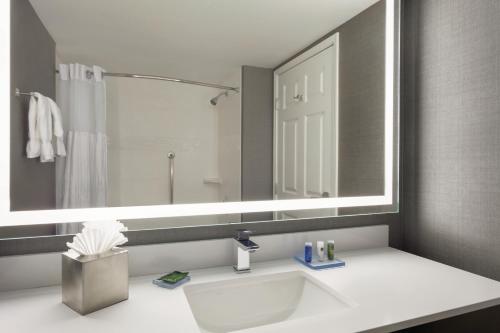 a white sink sitting under a mirror in a bathroom at Radisson Dallas North-Addison in Addison