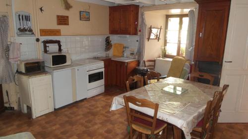 une cuisine avec une table et une cuisine avec des appareils électroménagers blancs dans l'établissement Maison de famille au plateau du Mezenc, à Les Vastres