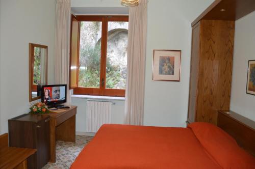 a bedroom with an orange bed and a window at Hotel La Bussola in Amalfi