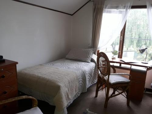 a bedroom with a bed and a desk and a window at Hospedaje Bernardita in Valdivia