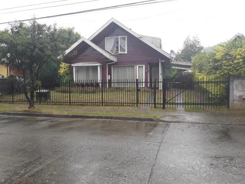 a house with a black fence in front of a street at Hospedaje Bernardita in Valdivia