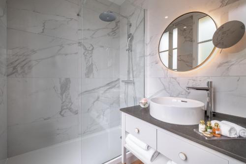 a white bathroom with a sink and a mirror at Hôtel Le Walt by Inwood Hotels in Paris