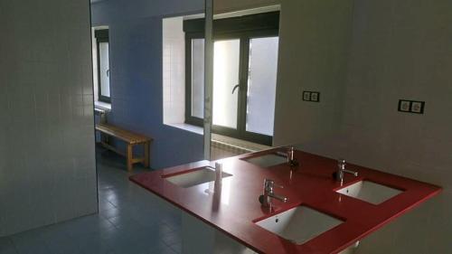 a bathroom with a red counter with three sinks at El cordal de laciana in Caboalles de Abajo