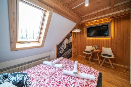 a bedroom with a bed and a tv and a window at Chałpa u Zbójnika in Zakopane