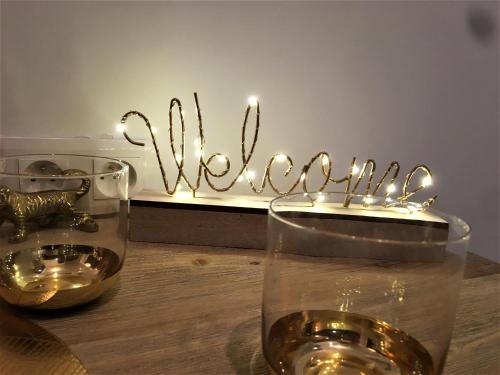 um copo de vinho numa mesa com um sinal de boas-vindas em GOLD Suite & Spa em Nantes