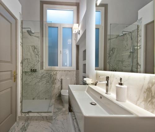ein weißes Bad mit einem Waschbecken und einem WC in der Unterkunft Acropolis TownHouseCo Suites in Athen