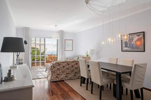 a dining room and living room with a table and chairs at Garajau I by An Island Apart in Caniço