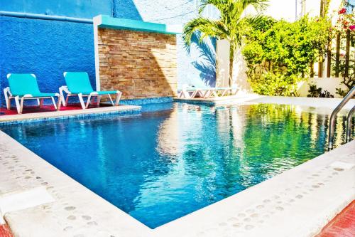 - deux chaises assises à côté de la piscine dans l'établissement Arrecifes Suites, à Puerto Morelos