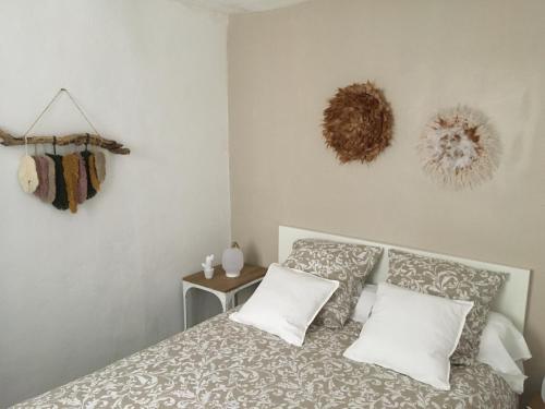 a bedroom with a bed with white pillows and a table at Cassis et ses trésors in Cassis