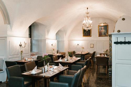 a dining room with tables and chairs and a chandelier at Hotel Schloss Lehen in Bad Friedrichshall