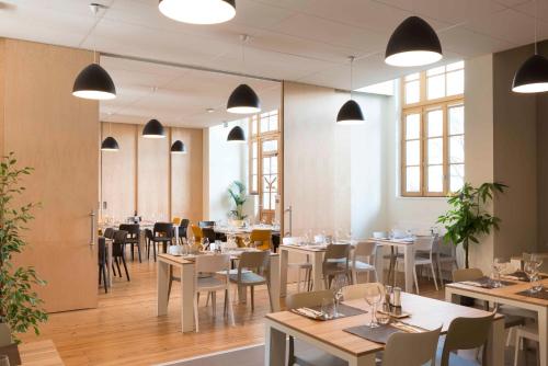 - une salle à manger avec des tables, des chaises et des fenêtres dans l'établissement Hotel Saint Louis Beaulieu - Bordeaux, à Bordeaux