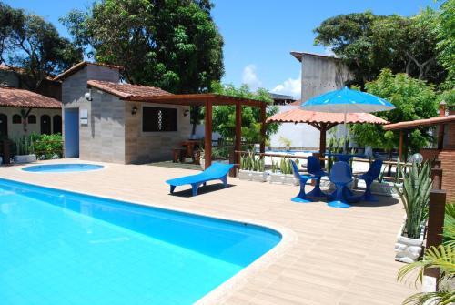 a swimming pool with blue chairs and umbrellas at Hotel Rusticos in Conceição da Barra