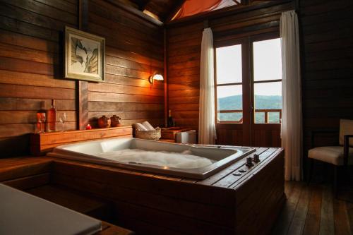 a large bath tub in a room with a window at Pousada Fogo Eterno in Urubici