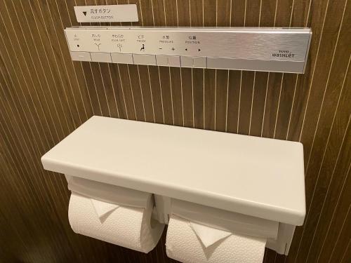 a white toilet in a bathroom with a sign above it at Sunset Beach Hotel in Chatan