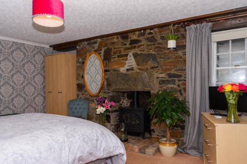 1 dormitorio con pared de piedra, cama y chimenea en Stravaig B&B, en Cullen