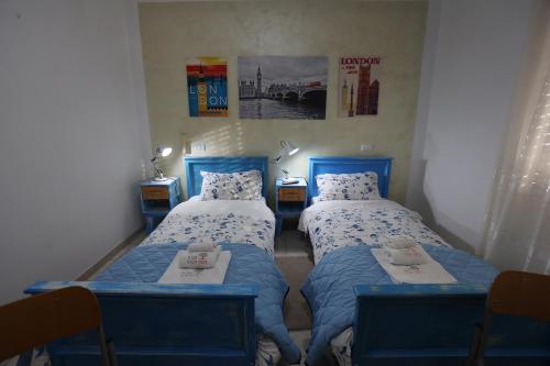 two beds in a room with blue chairs at La Casa del Gelso Fiorito in Eboli