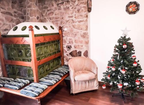 a christmas tree and a chair next to a fireplace at BeB Sas da Rocia in Soraga