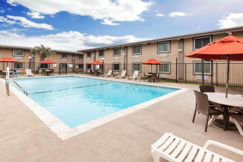 a pool at a hotel with tables and chairs at Super 8 by Wyndham Beaumont I-10 College St in Beaumont