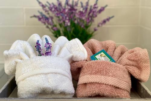 a bunch of towels in a box with flowers at Kauri Glen BnB in Te Arai
