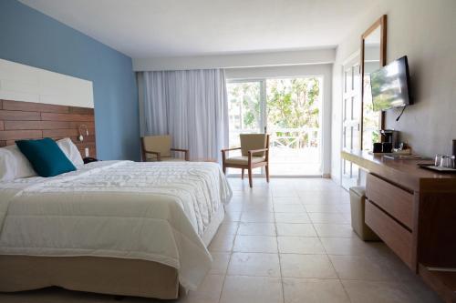 a hotel room with a bed and a sliding glass door at Viva Fortuna Beach by Wyndham, A Trademark All Inclusive in Freeport