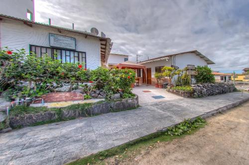 a building with flowers and plants in front of it at Hostal Villamil in Puerto Villamil