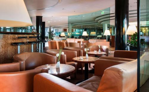 a restaurant with brown leather chairs and tables at Radisson Blu Park Hotel & Conference Centre in Dresden