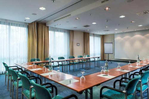 a conference room with tables and chairs and a screen at Radisson Blu Fürst Leopold Hotel in Dessau