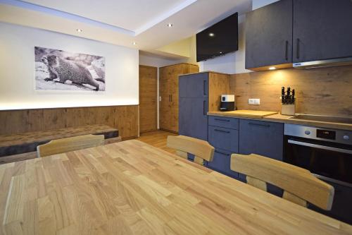 a kitchen with a large wooden table and blue cabinets at Waidmannsruh Appartements in Gerlos
