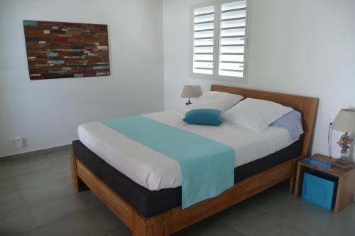 ein Schlafzimmer mit einem großen Bett mit einem blauen Kissen in der Unterkunft Douceurs Caraïbes, Gîte Papaye. in Bouillante