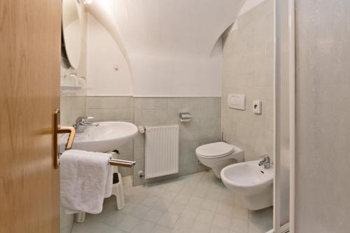 a white toilet sitting next to a white sink in a bathroom at Residence Chiavi D'Oro - Goldener Schlüssel in Bressanone