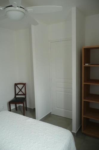 a bedroom with a bed and a chair and a closet at Douceurs Caraïbes, Gîte Coco. in Bouillante