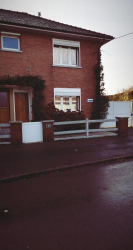 a red brick house with a fence in front of it at Hôte "Il était une fois" in Hesdin
