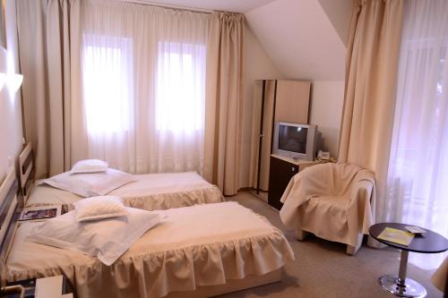 a hotel room with two beds and a television at Suior Resort Baza in Baia-Sprie