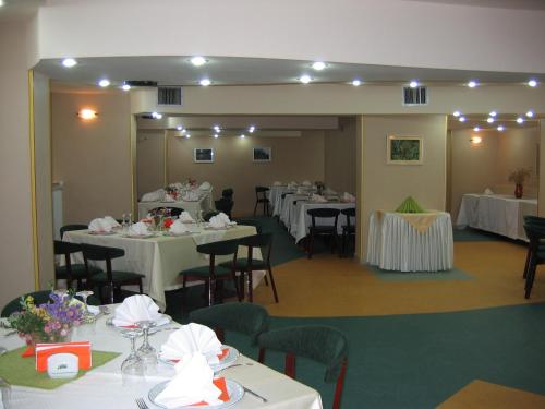 a room filled with tables and chairs with white tablecloths at Suior Resort Baza in Baia-Sprie