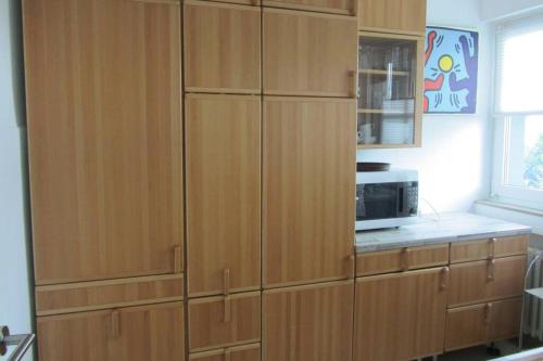 a large wooden cabinet in a kitchen with a microwave at Große Wohnung 20 km von Köln bis zu 17 Personen in Rösrath