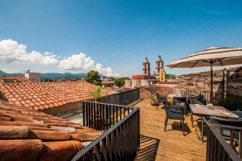 a balcony with a table and chairs and an umbrella at Múbú Hotel Boutique in Valle de Bravo