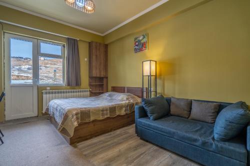 a bedroom with a bed and a couch and a window at Cozy studio in Gudauri in Gudauri