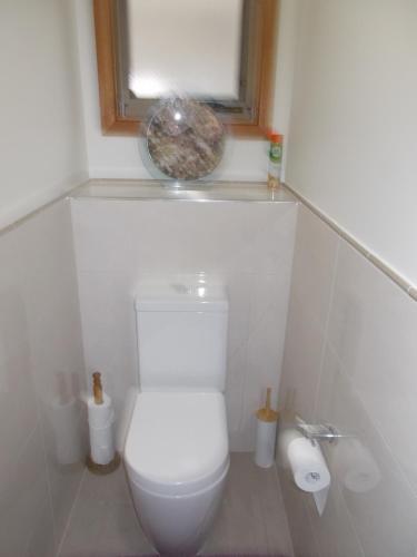 a white bathroom with a toilet and a window at Costa Plenti Southend BnB in Southend
