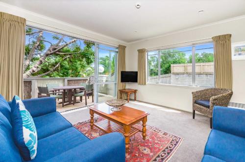 a living room with a blue couch and a table at Raumati Sands Resort in Paraparaumu Beach