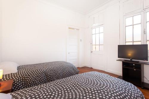 a bedroom with two beds and a flat screen tv at Italia Suite in Santiago