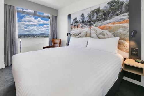 um quarto com uma grande cama branca e uma janela em Hotel Launceston em Launceston