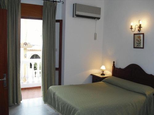 a bedroom with a green bed and a window at Hotel Chipiona in Chipiona