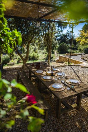a wooden picnic table with plates and drinks on it at Mas de l'Arlequi in Rojals