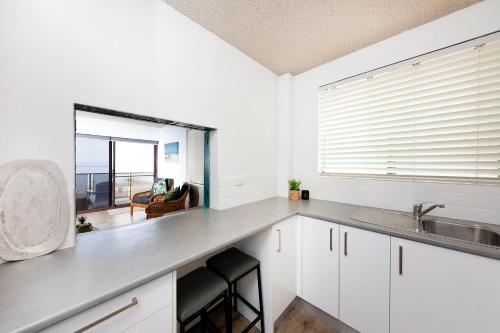 a kitchen with white cabinets and a sink and a window at Hibiscus Unit 4, 24 North St, Forster in Forster