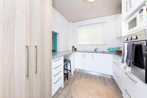 a kitchen with white cabinets and a sink at Hibiscus Unit 4, 24 North St, Forster in Forster